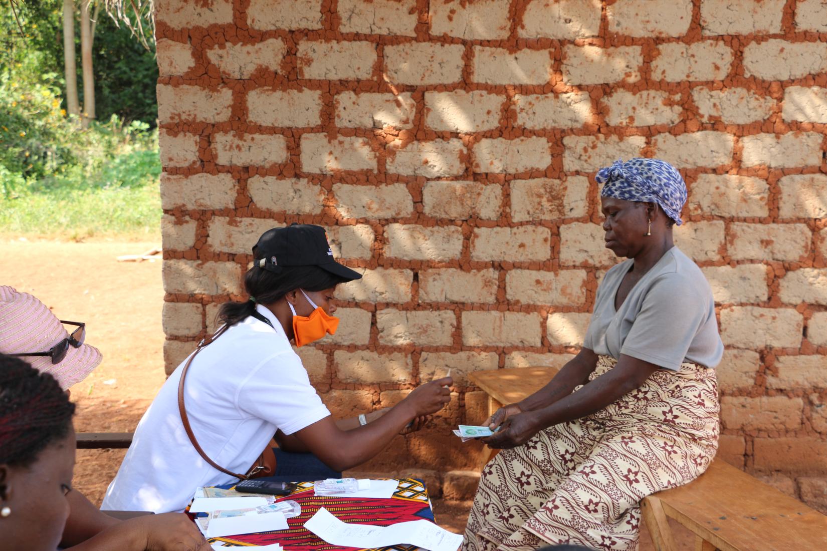 Une femme reçoit de l’argent dans le cadre du projet Cash4Covid de l’équipe de NRC. 
