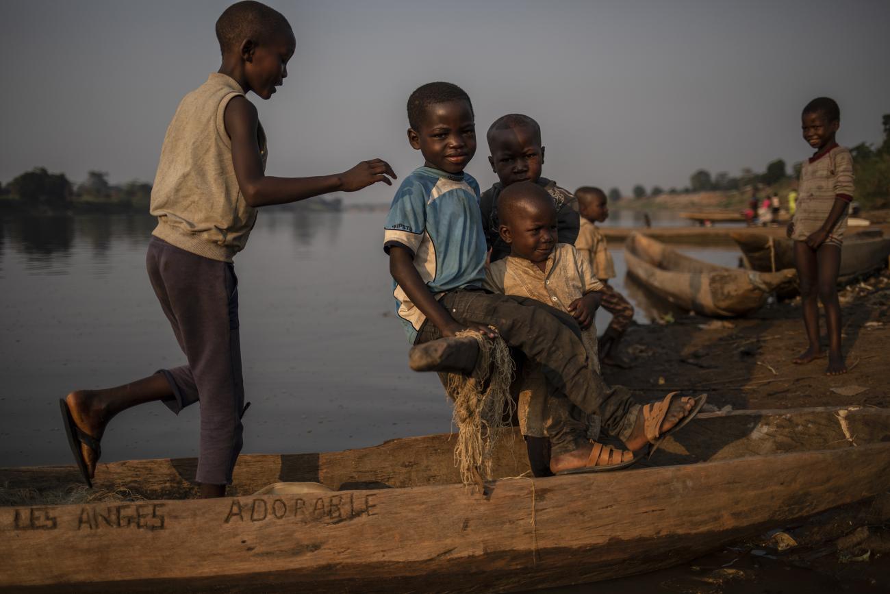 Des enfants déplacés jouent autour des pirogues traditionnelles en bois sur les rives du fleuve Oubangui, Bangui, RCA.