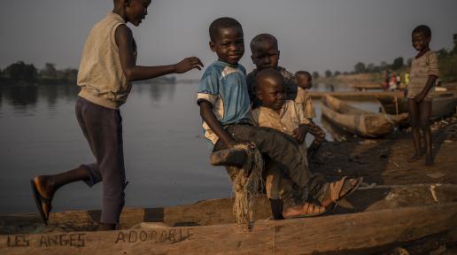 Des enfants déplacés jouent autour des pirogues traditionnelles en bois sur les rives du fleuve Oubangui, Bangui, RCA.